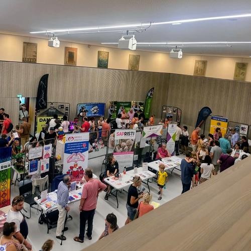 In einem Saal sind viele Stände aufgebaut, an denen sich Menschen über Sportangebote informieren  In einem Saal sind viele Stände aufgebaut, an denen sich Menschen über Sportangebote informieren