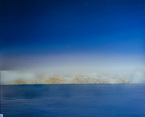 Eine Insel in Naturfarbe liegt zwischen Meer und Himmel in Blau Eine Insel in Naturfarbe liegt zwischen Meer und Himmel in Blau