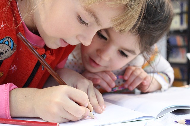 Zwei Kinder schreiben mit Stiften